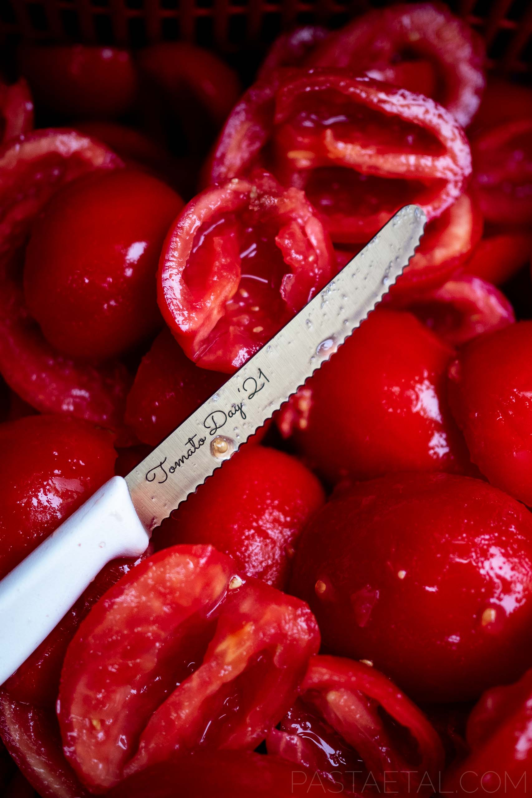 https://pastaetal.com/wp-content/uploads/2021/03/close-up-of-engraved-tomato-knife-on-box-of-halved-roma-tomatoes.jpg